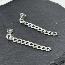 Closeup of dangle stud earrings in polished sterling silver curb chain design