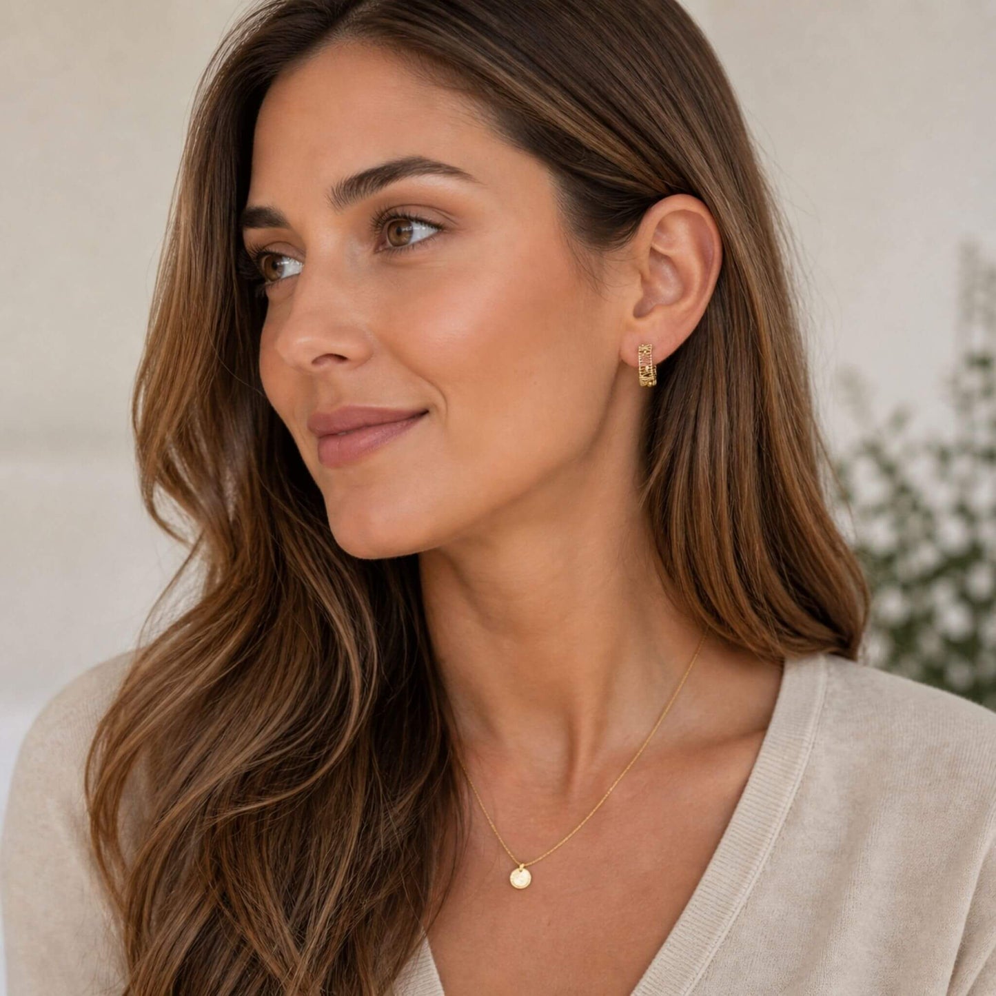 Woman wearing small 14K gold plated hoop earrings with a modern wire wrapped design