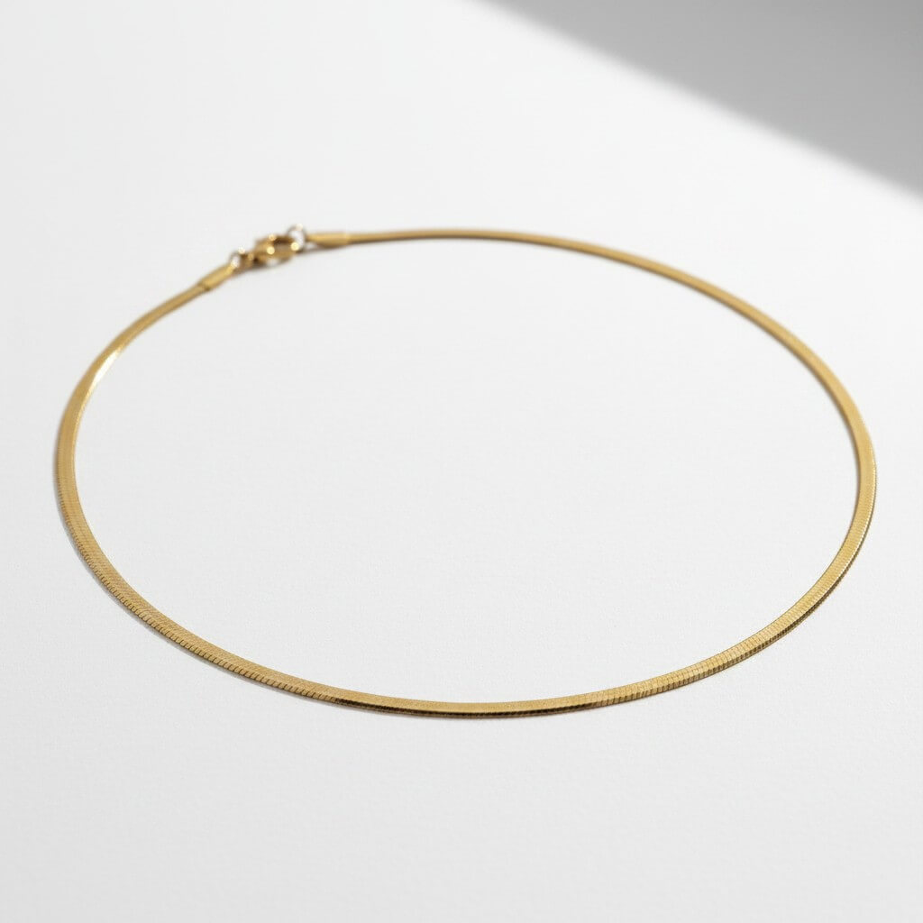 18" gold herringbone necklace on flat surface, showing 3mm flat serpentine chain with lobster claw clasp, 18K gold plated stainless steel