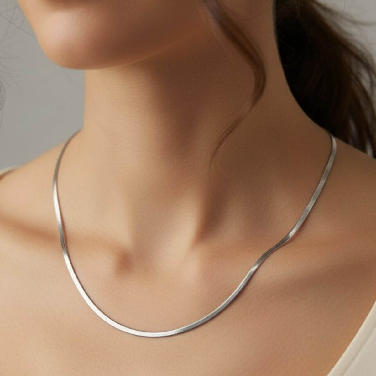 Close-up of silver herringbone chain necklace at collarbone, 3mm width stainless steel waterproof jewelry