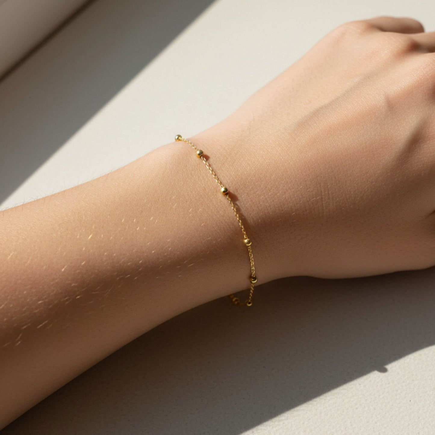 18K gold plated ball chain bracelet shown on wrist in natural sunlight