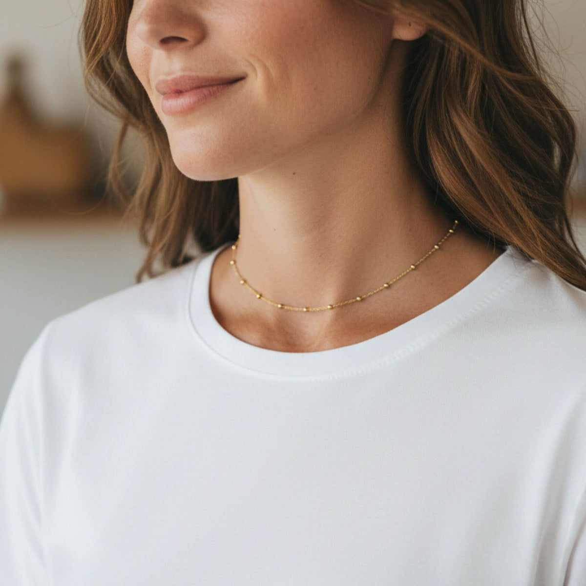 Dainty 18K gold plated bead station necklace adjustable 14 to 16 inches shown from side angle on model.