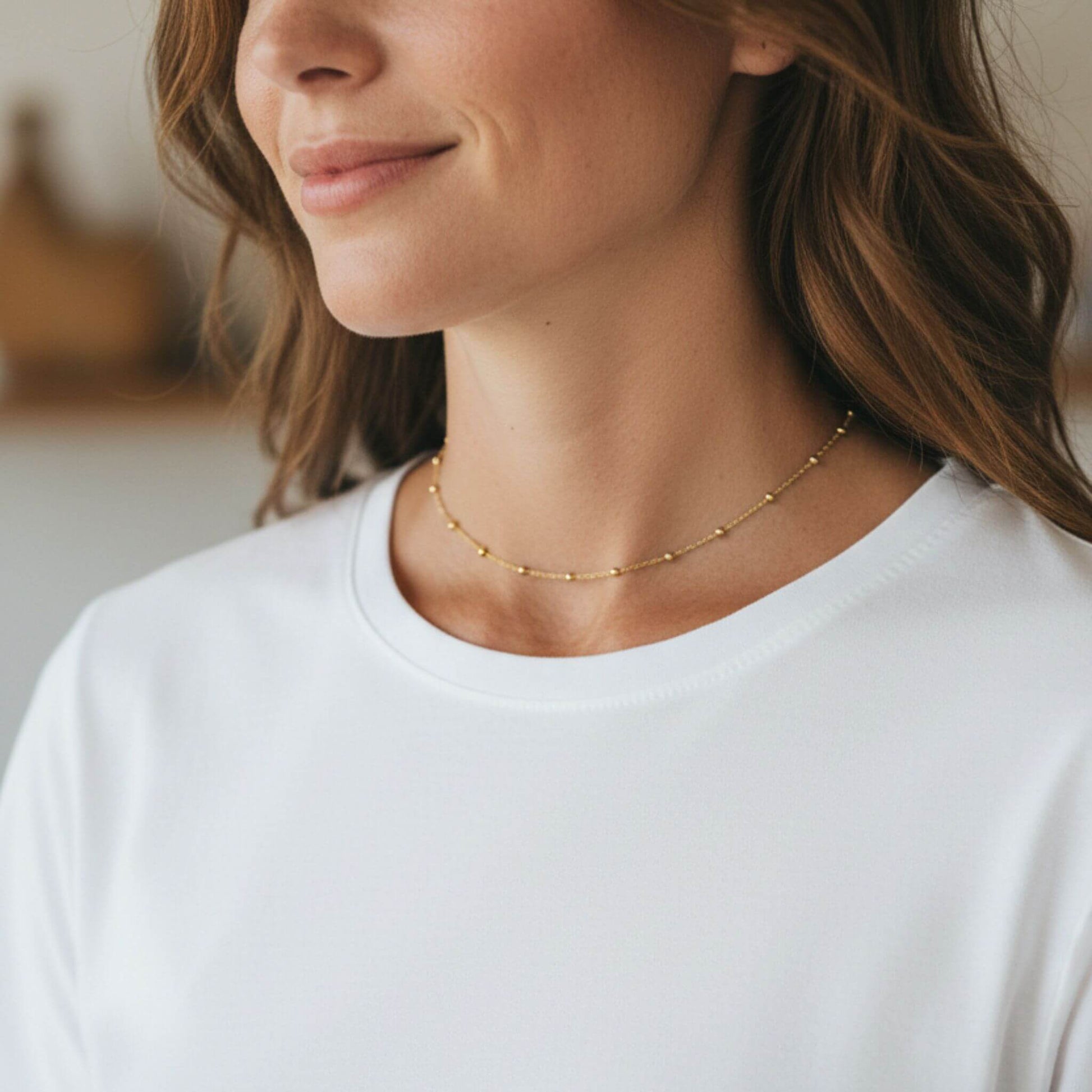 Dainty 18K gold plated bead station necklace adjustable 14 to 16 inches shown from side angle on model.