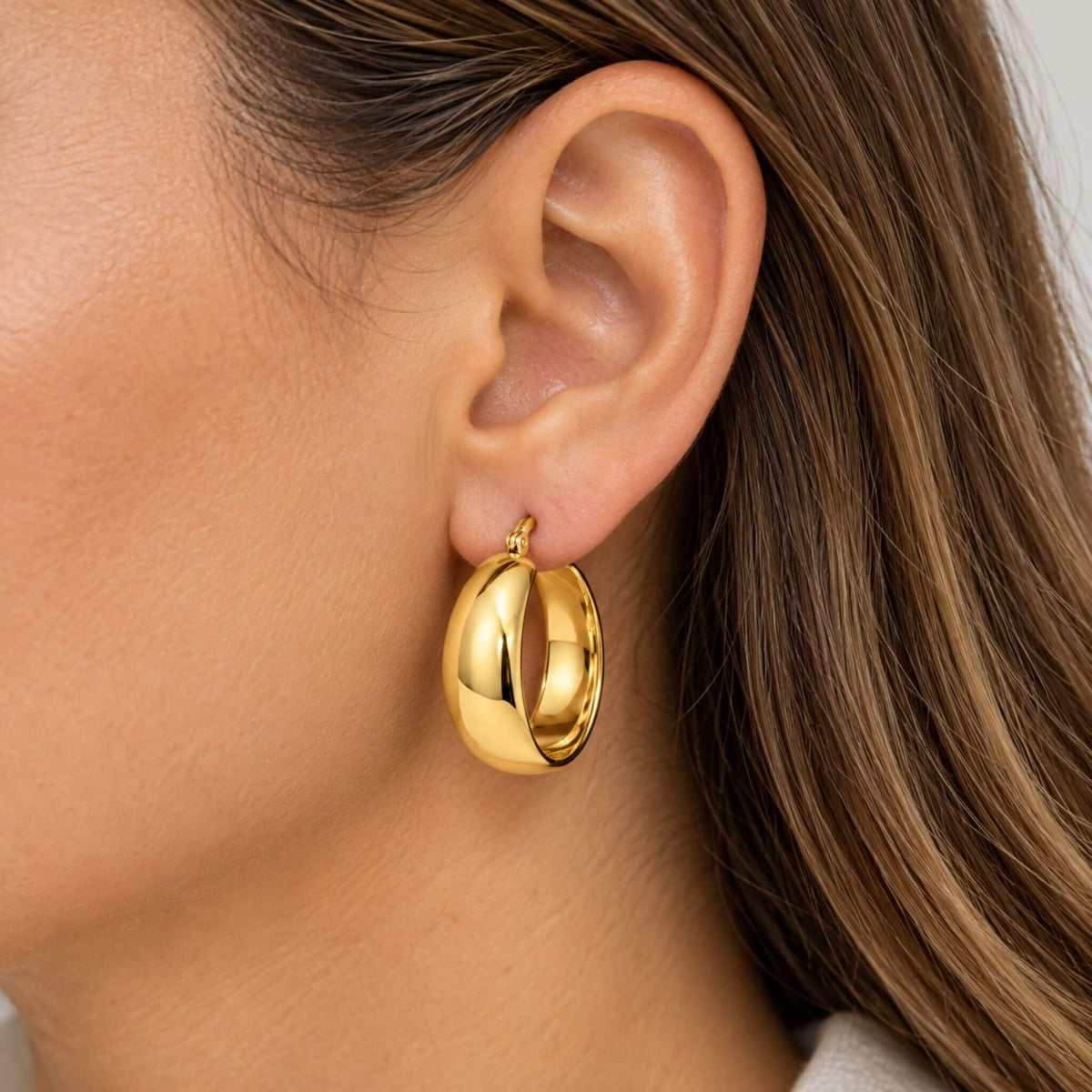 Close-up of 18K gold plated chunky hoop earring worn on ear