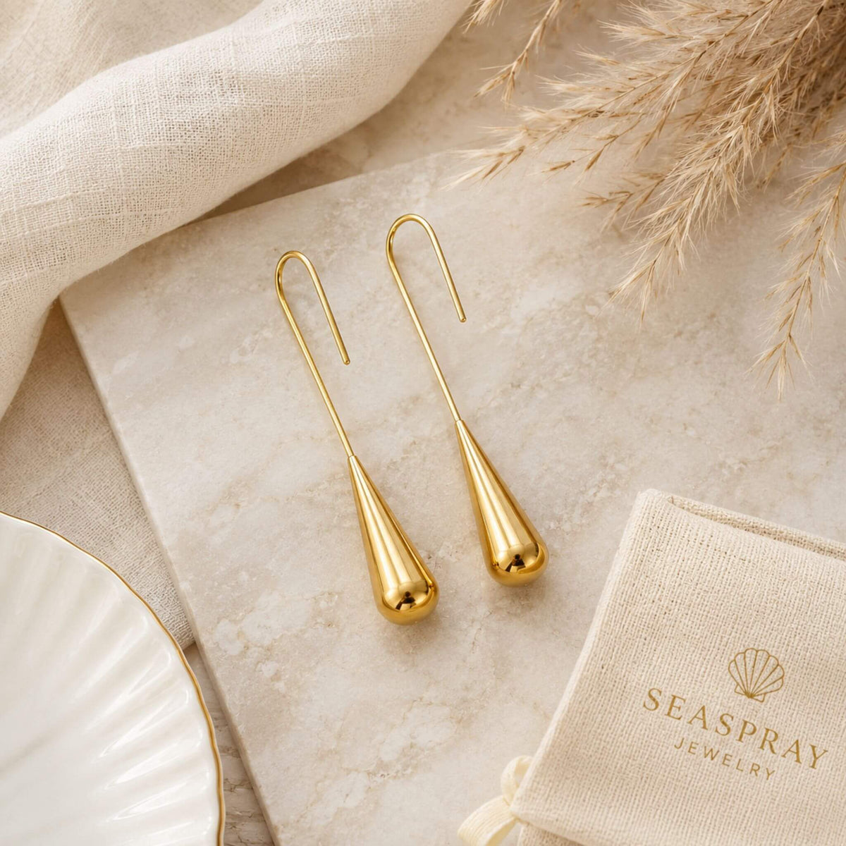 Flat lay of 18K gold plated gold dangle earrings on a luxury marble surface with minimalist styling and premium gift-ready presentation.