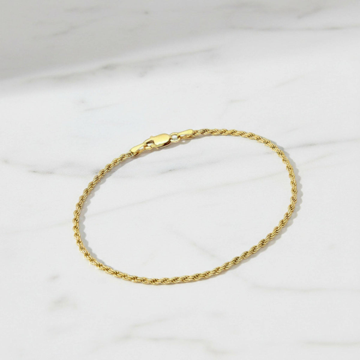 18K gold plated rope chain bracelet with lobster clasp displayed on white marble surface