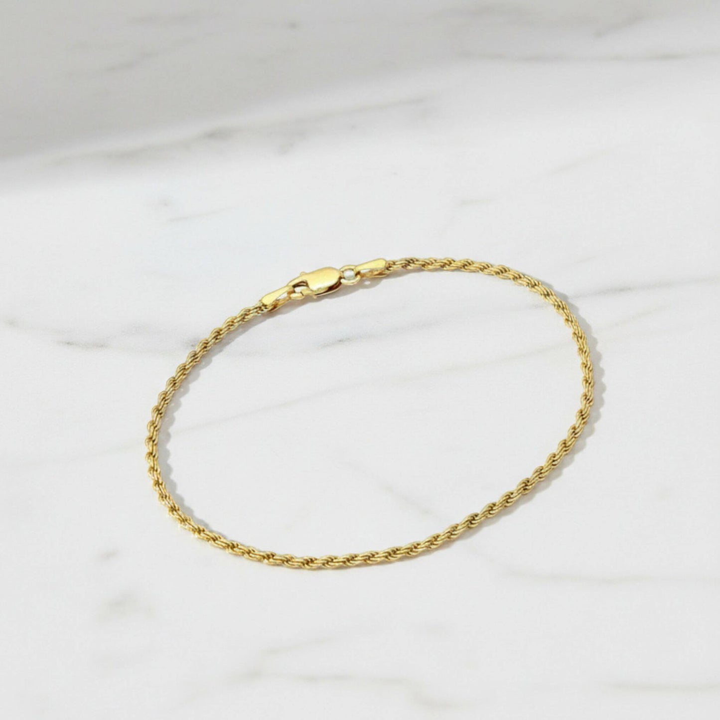 18K gold plated rope chain bracelet with lobster clasp displayed on white marble surface