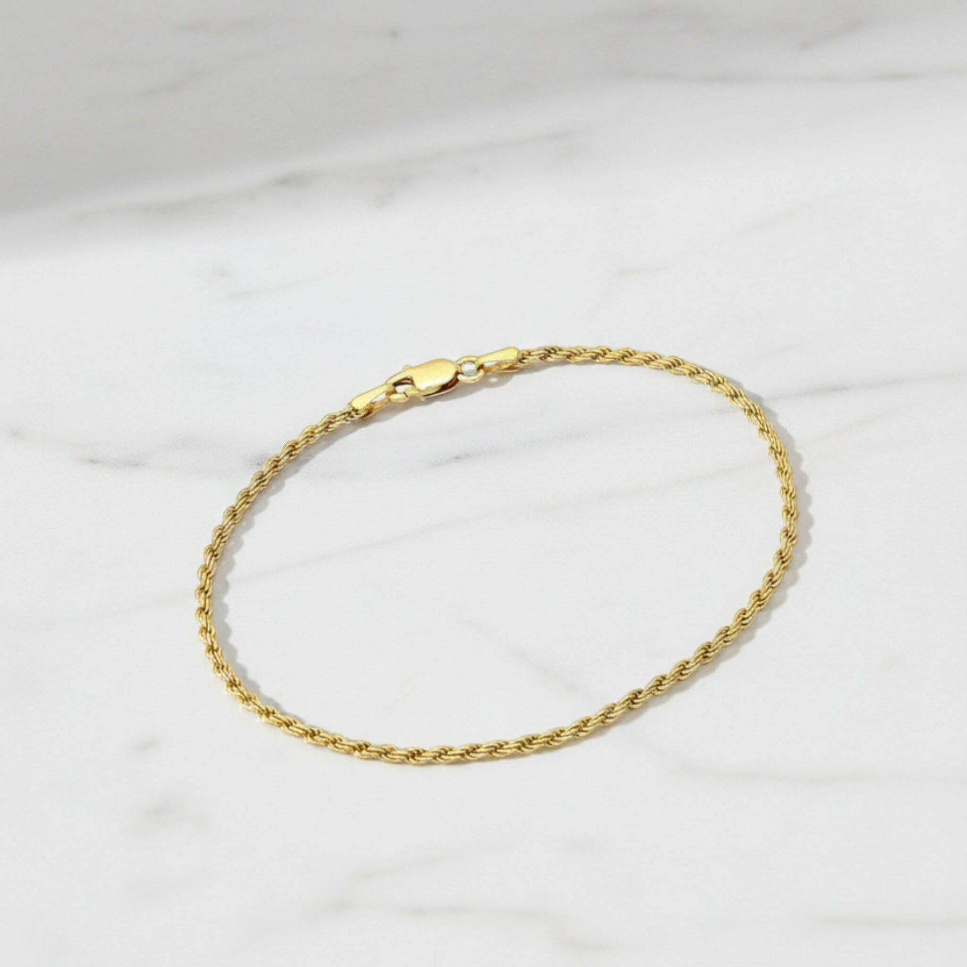 18K gold plated rope chain bracelet with lobster clasp displayed on white marble surface