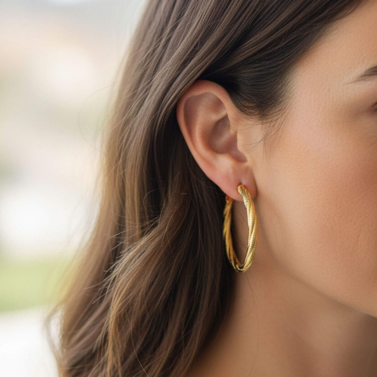 Close-up of 18K gold plated twist stripe hoop stud earrings with textured stripe detail