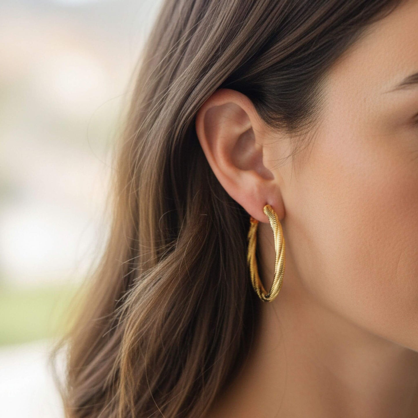 Close-up of 18K gold plated twist stripe hoop stud earrings with textured stripe detail