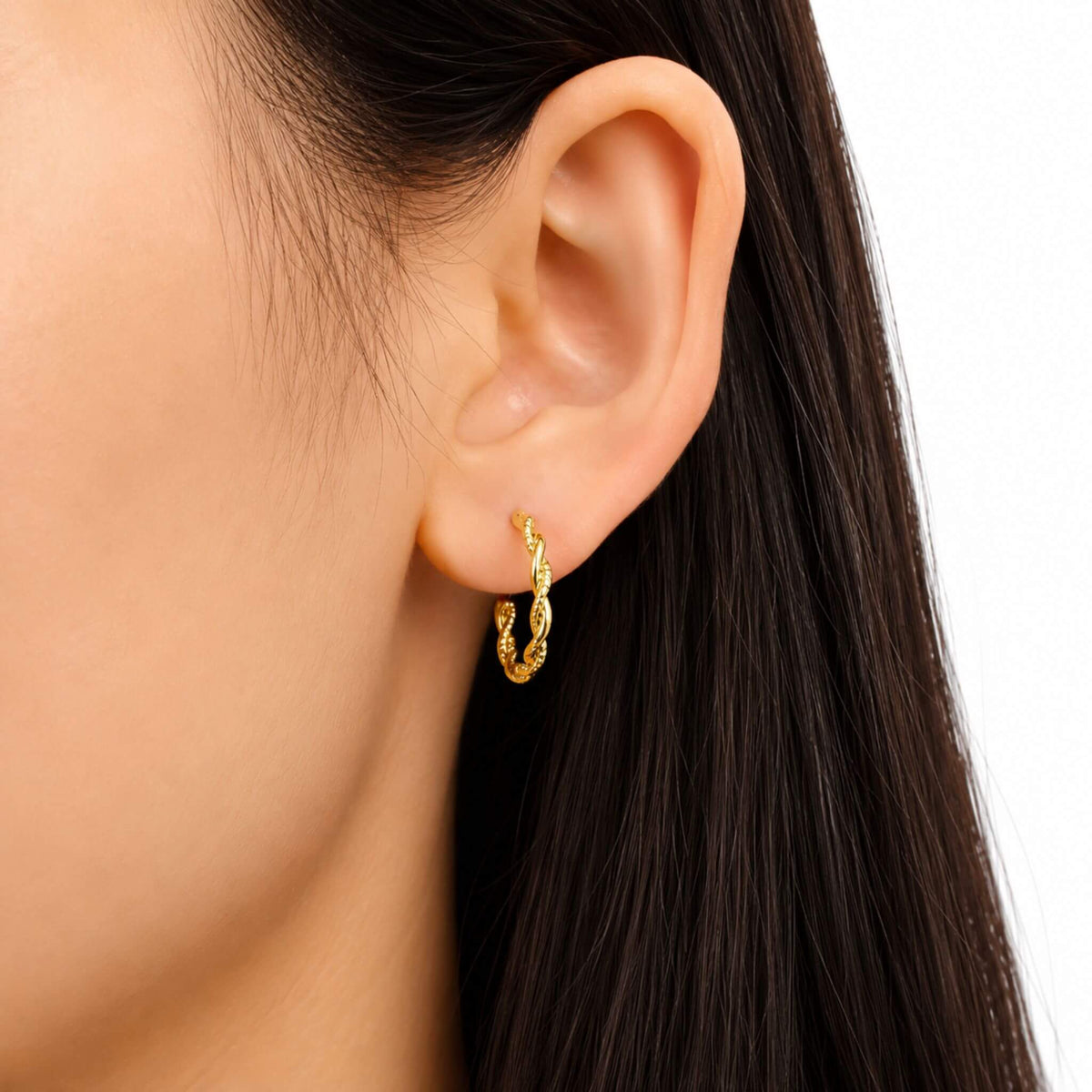 Close-up of 18K gold plated twisted rope hoop earrings worn on the ear showing the rope twist detail.