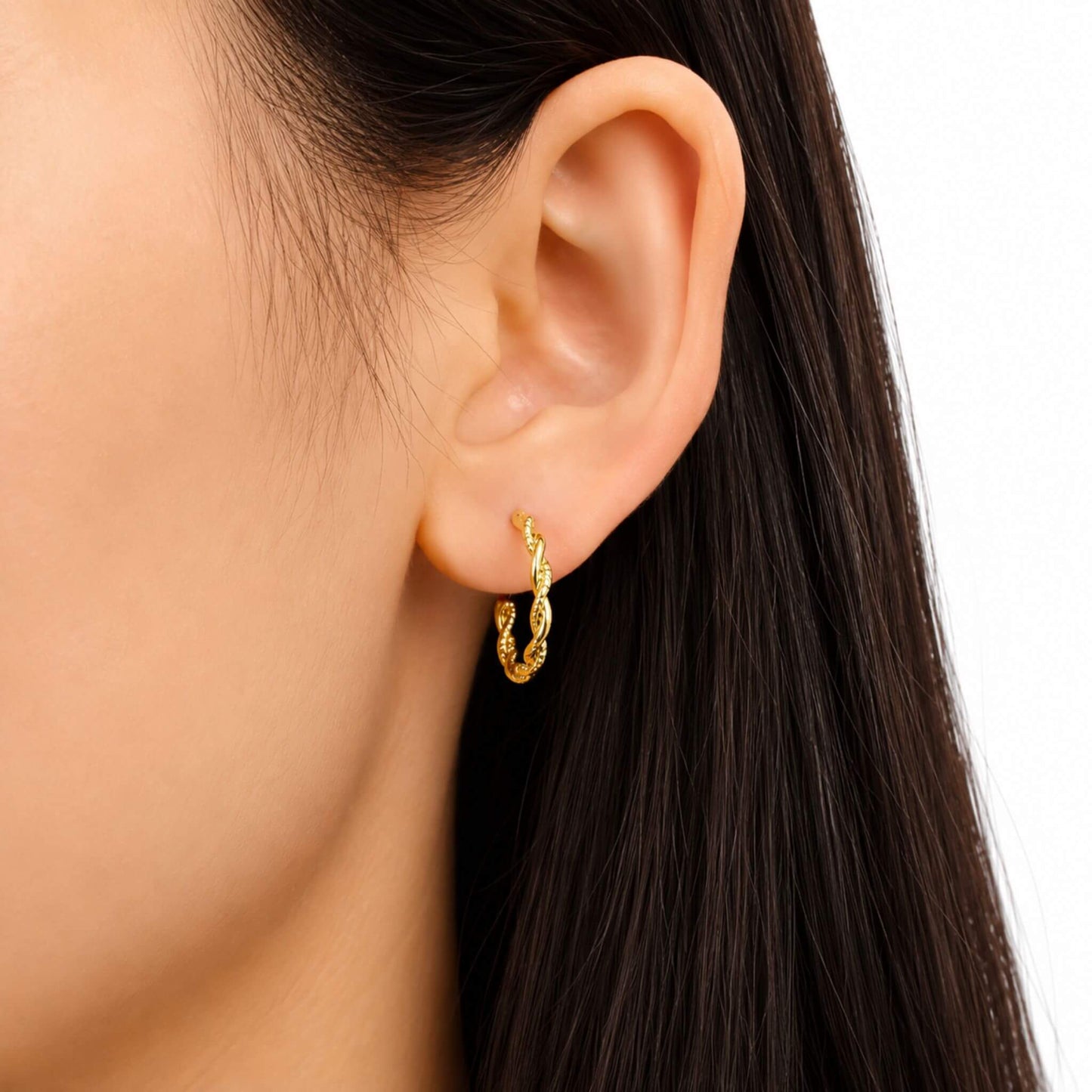 Close-up of 18K gold plated twisted rope hoop earrings worn on the ear showing the rope twist detail.