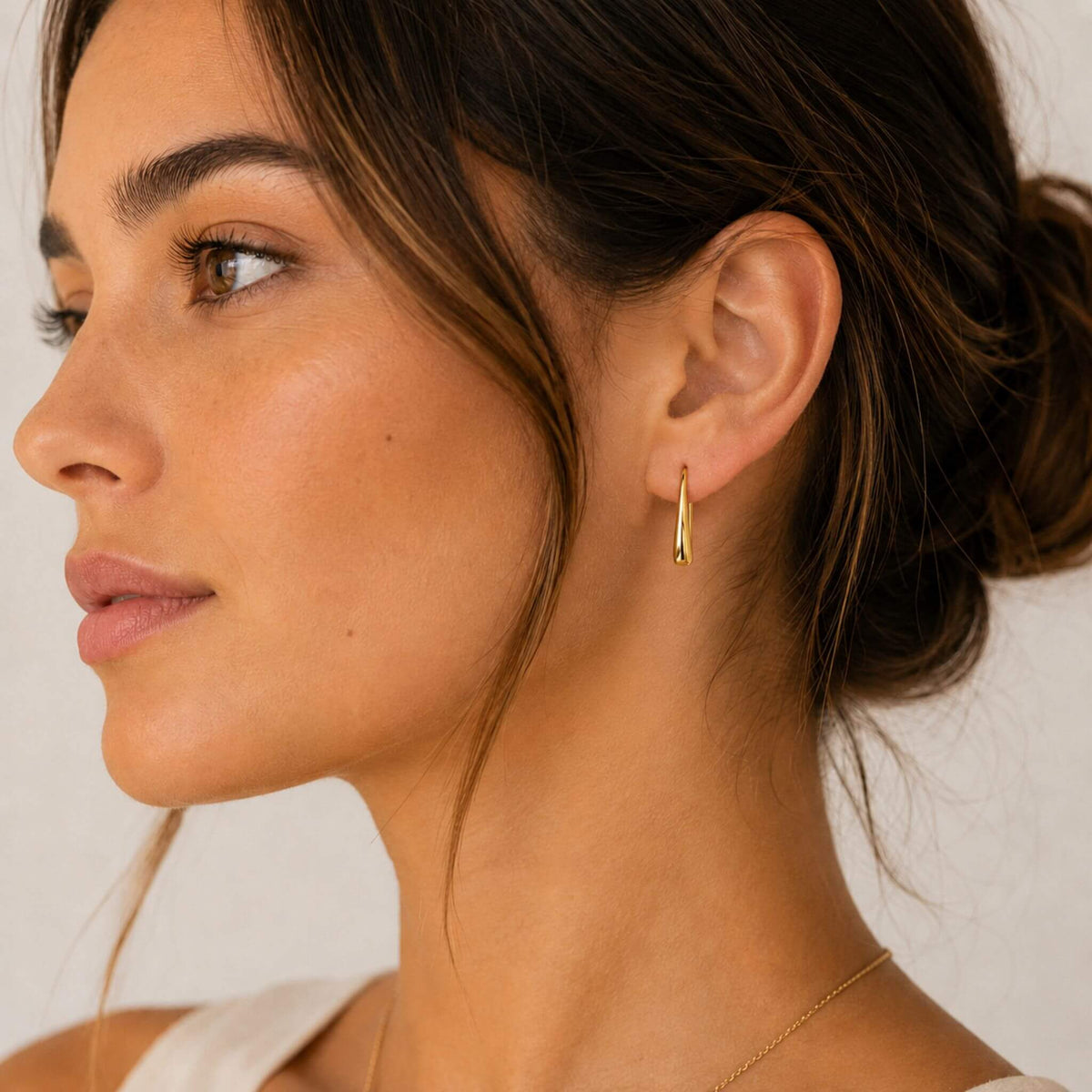 Model wearing 18K gold plated stainless steel teardrop hook earrings in a minimalist side profile view.