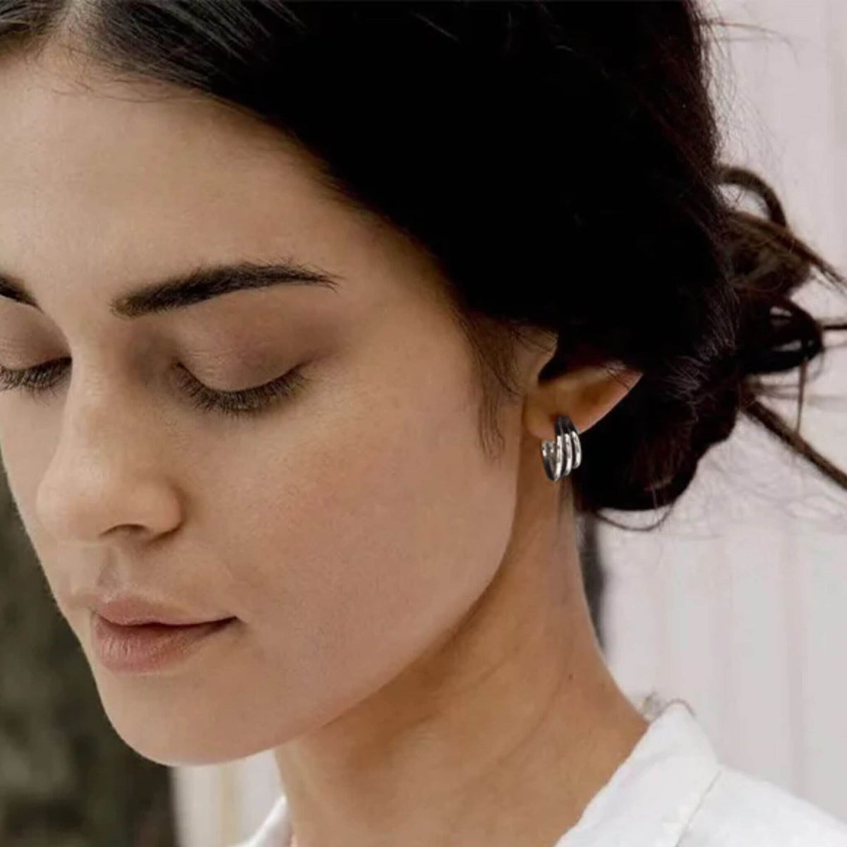 Close up of silver multilayer hoop earrings worn on ear