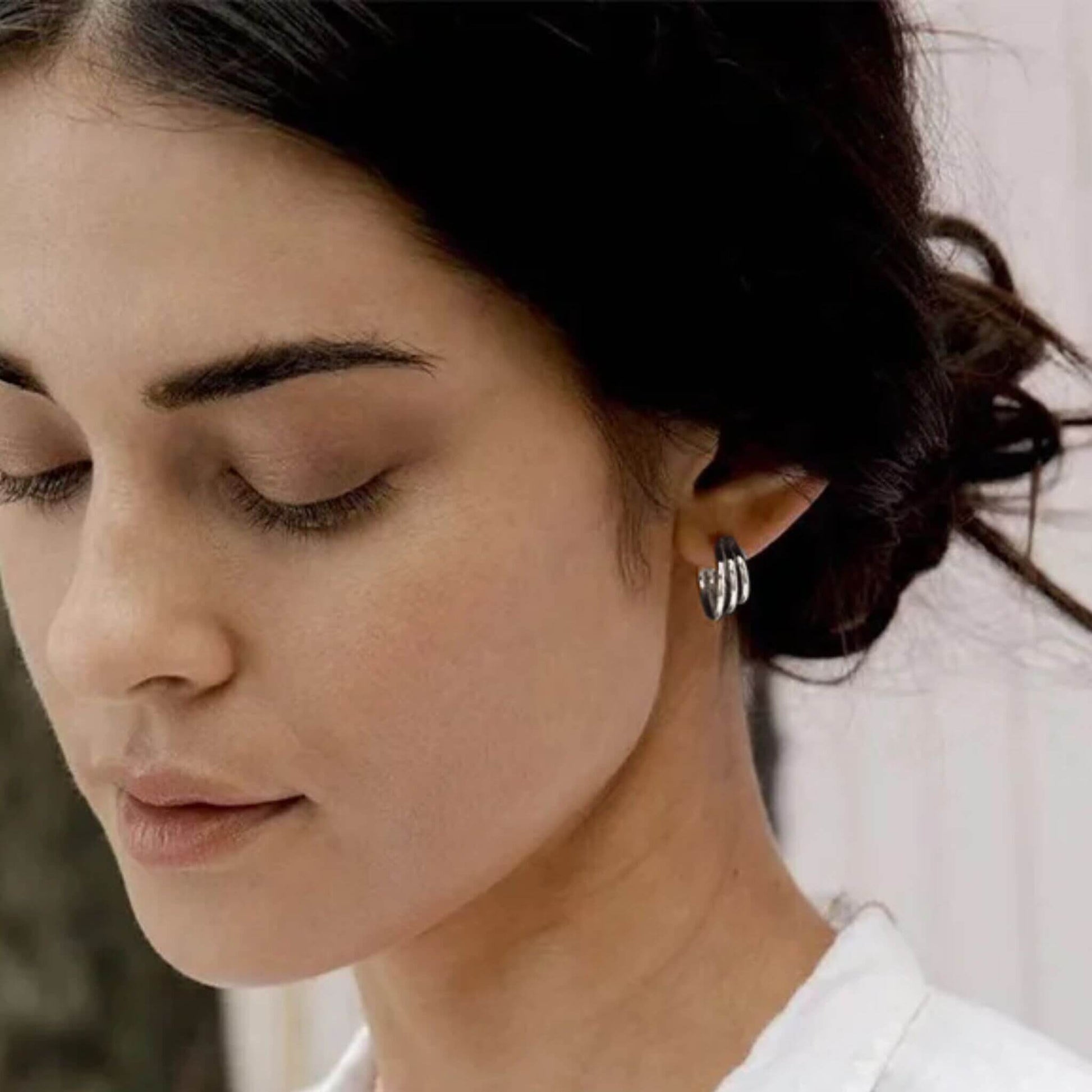Close up of silver multilayer hoop earrings worn on ear
