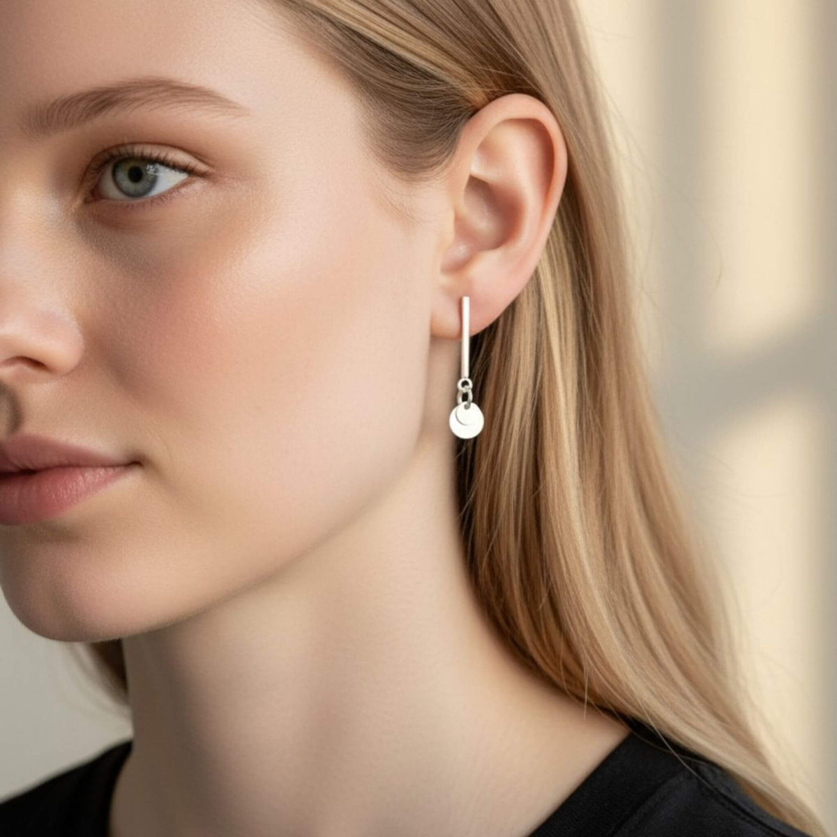 Close-up of 925 sterling silver bar stud earring with double circle disc drop on model's ear, showing polished finish and disc movement