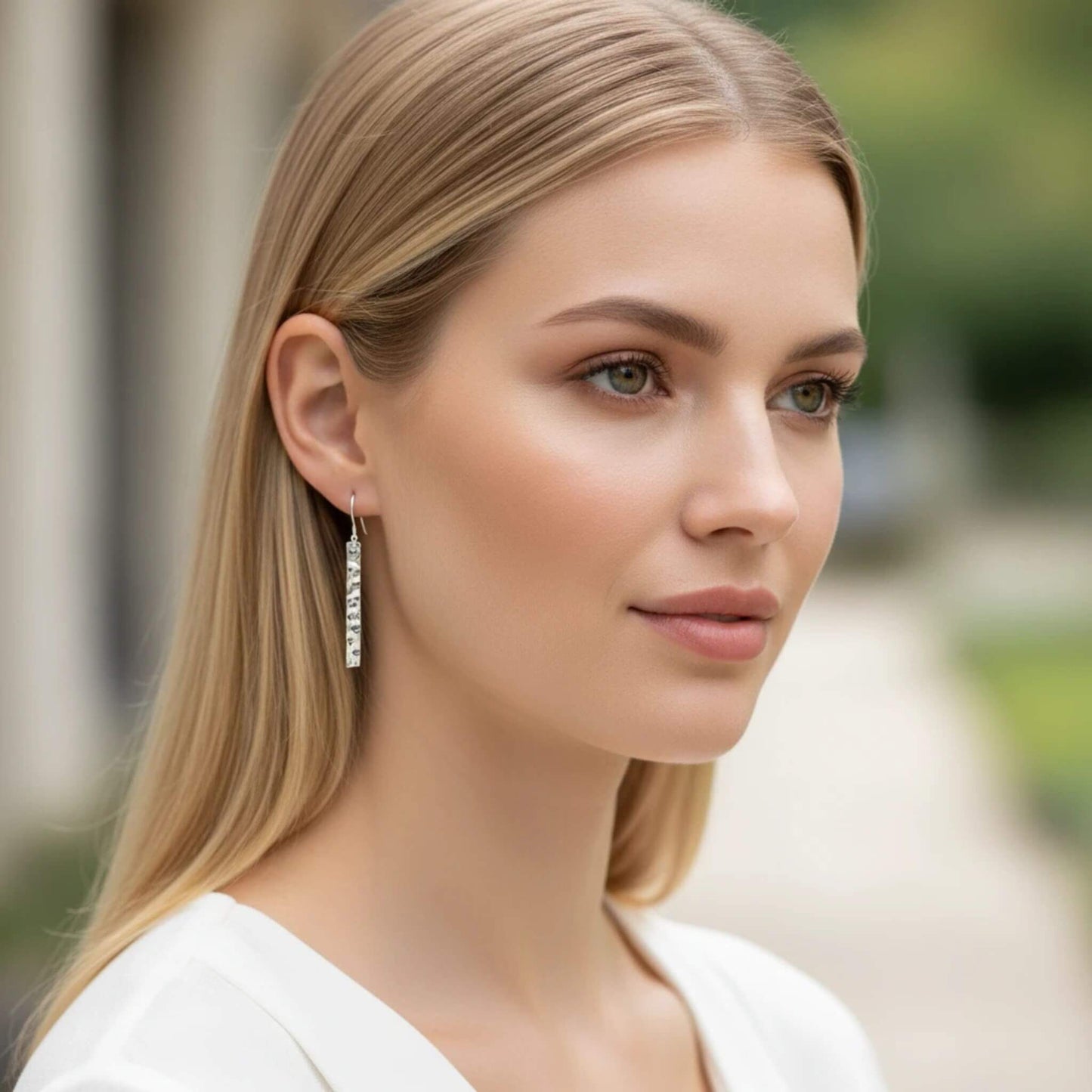 Long hammered sterling silver bar earrings on blonde model in profile view, showing full 41mm drop length and artisan-textured silver surface