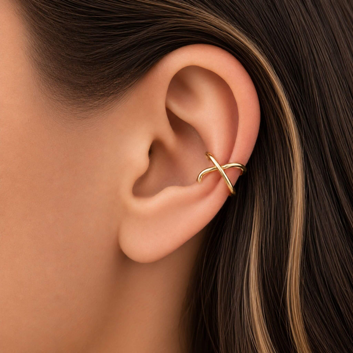 925 Sterling Silver Cross Knot Ear Cuff in 14K gold plated finish worn on the ear featuring a minimalist no piercing ear cuff design.