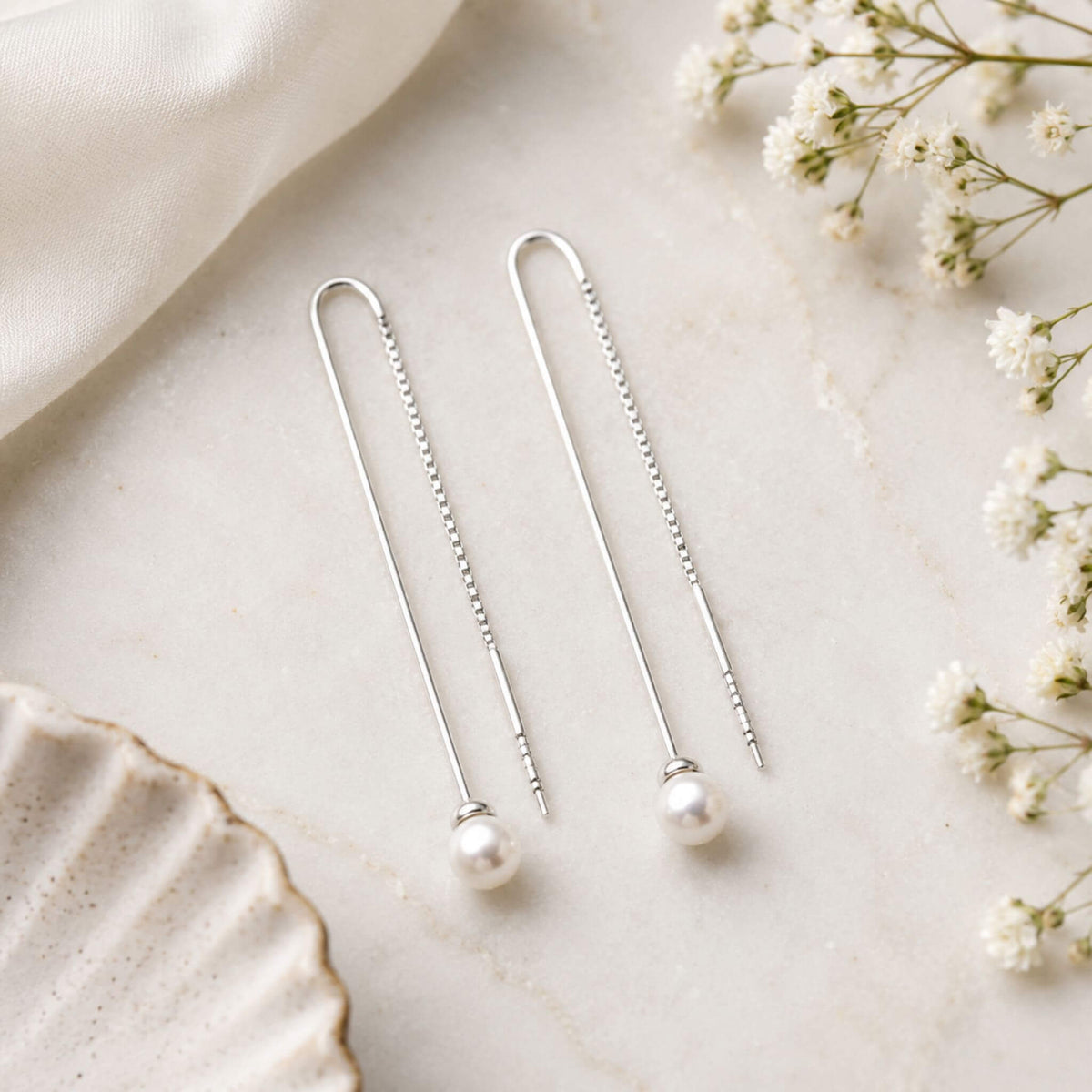 Freshwater pearl dangle earrings in sterling silver displayed on neutral background
