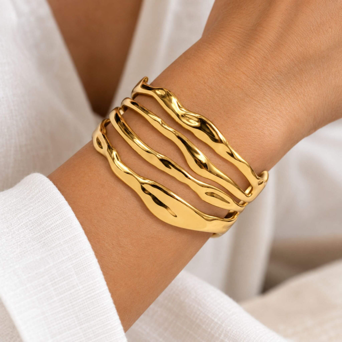 Gold cuff bracelet for women shown on wrist with a wide sculptural wave design
