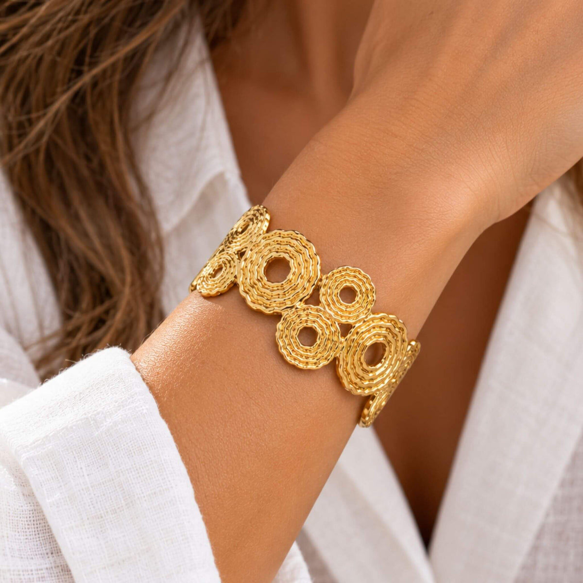 Woman wearing a gold cuff bracelet with textured open circle design