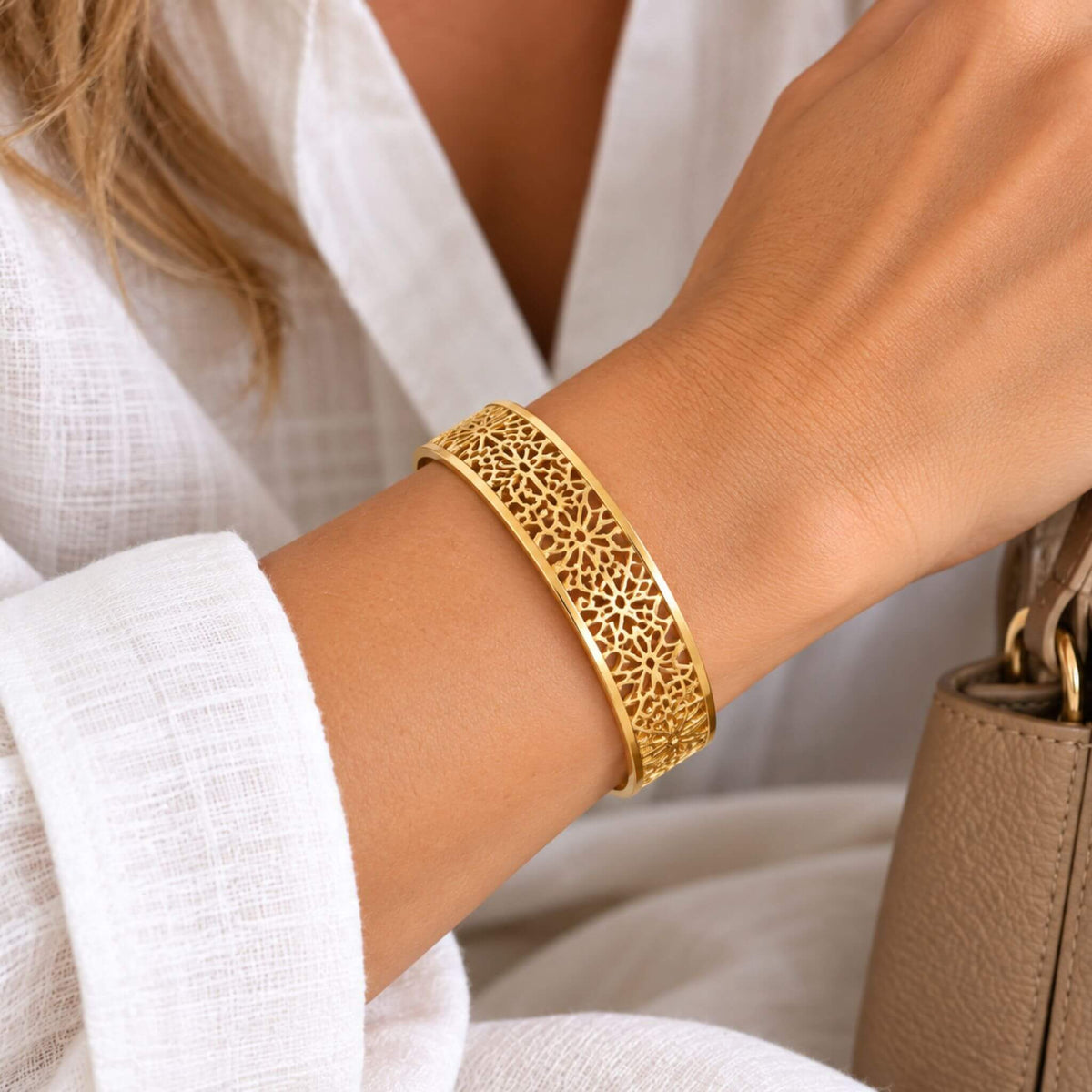 Gold filigree cuff bracelet for women with intricate openwork pattern worn on the wrist