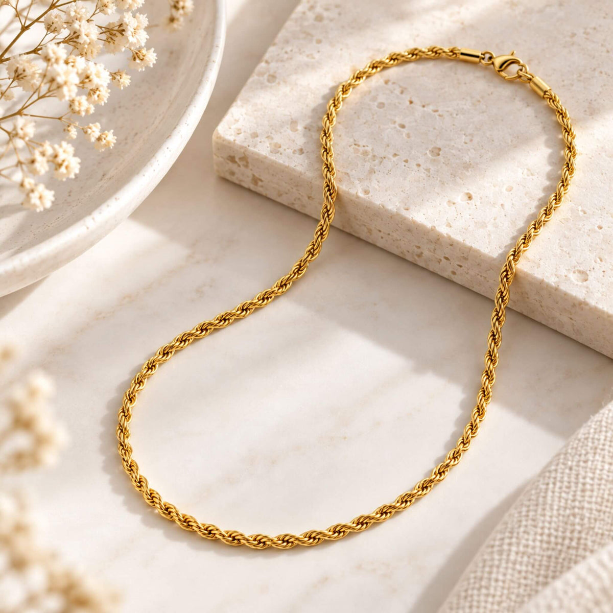 18K gold plated rope chain necklace styled on a neutral marble surface