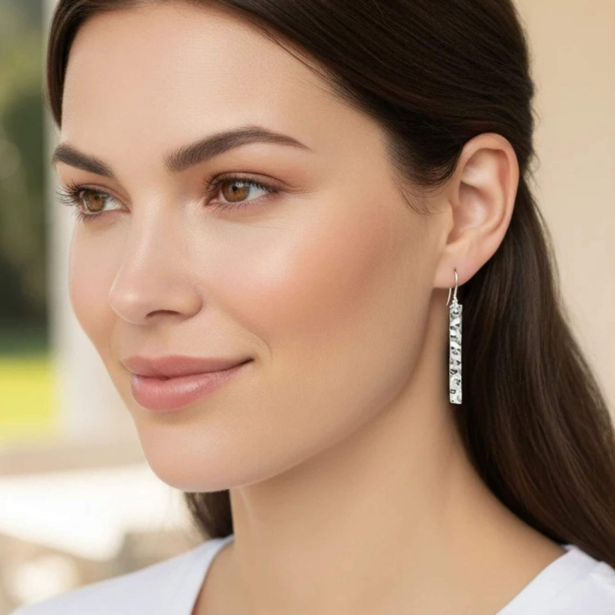 Hammered 925 sterling silver bar drop earring worn by model with brown hair, showing long rectangle dangle below earlobe with French wire hook