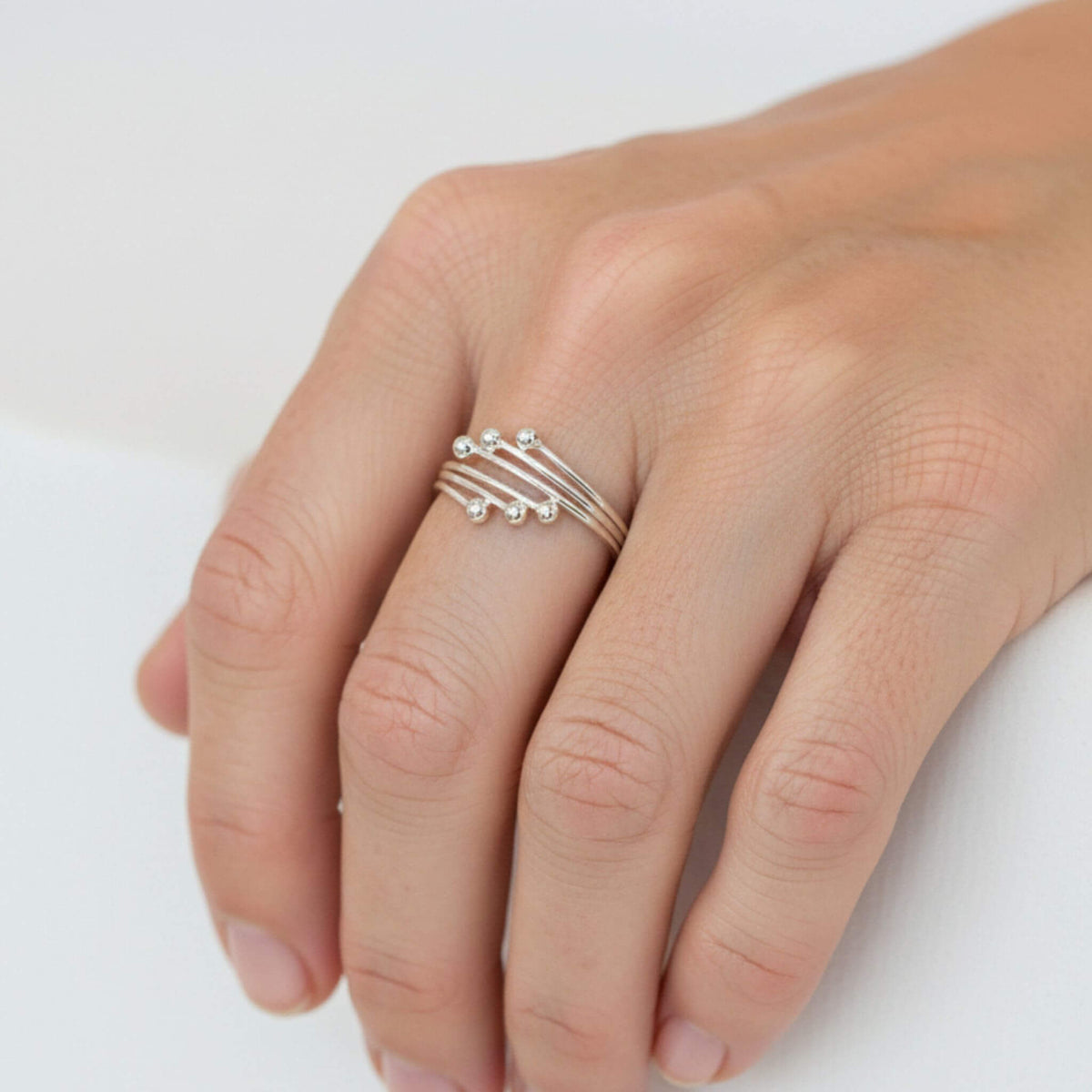 Minimalist sterling silver adjustable ball ring worn on finger