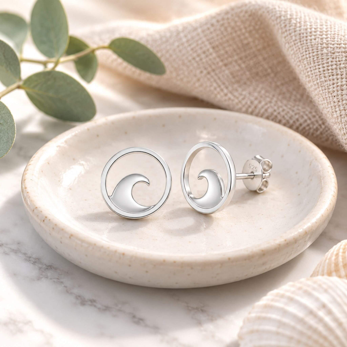 Ocean wave earrings in sterling silver displayed in a jewelry dish