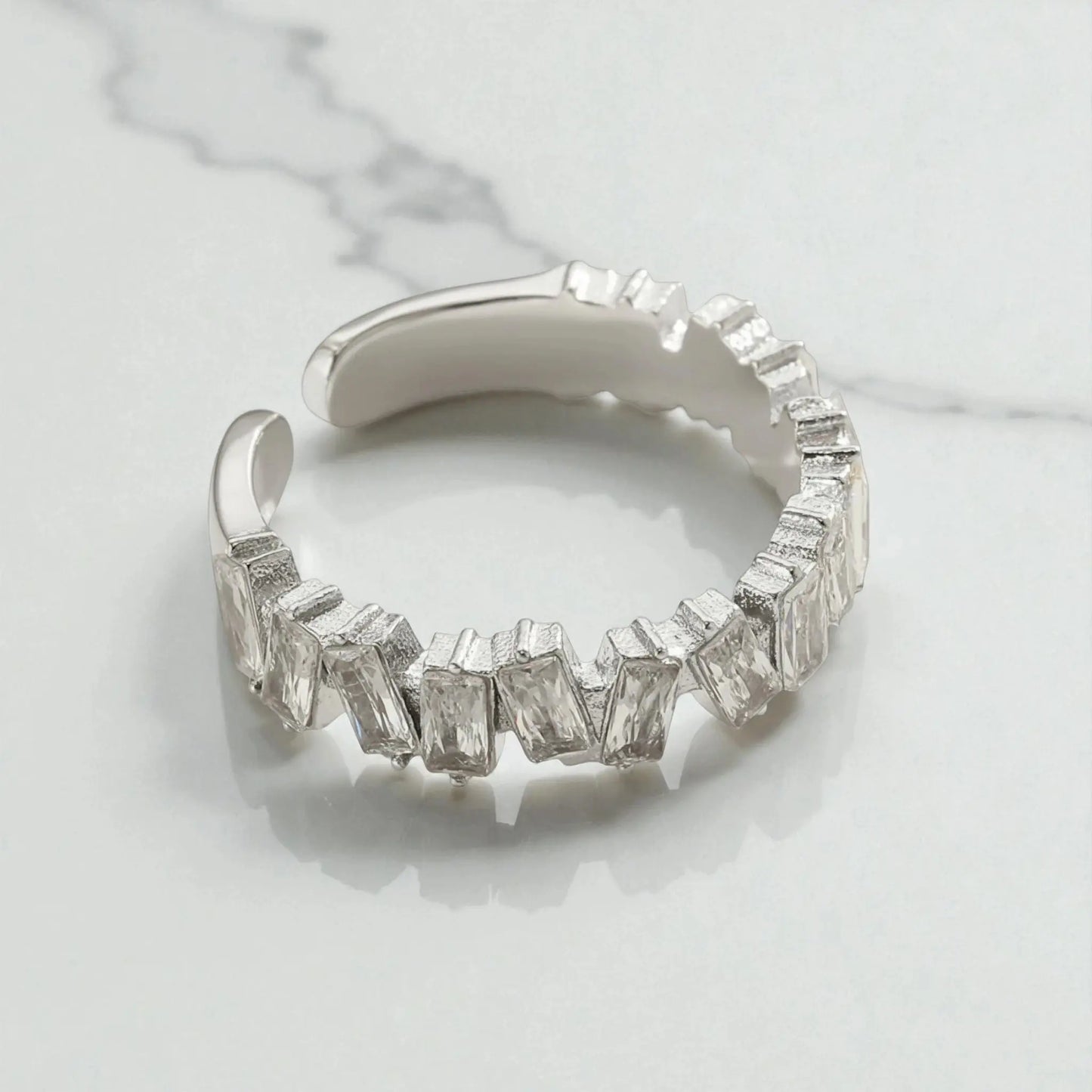 Silver 5A cubic zirconia open ring with rectangular stones displayed on light marble surface showing adjustable design and sparkle