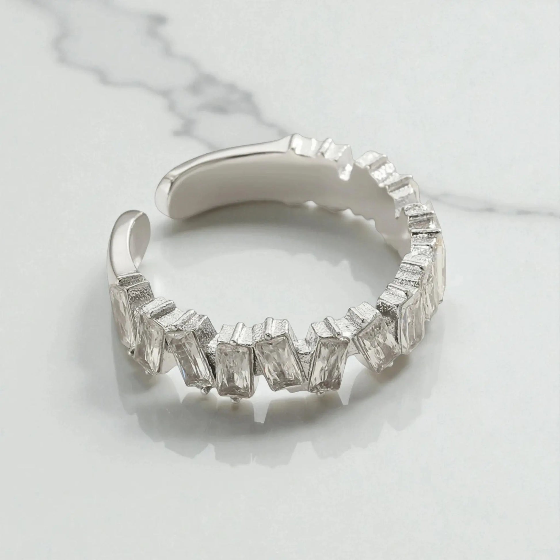 Silver 5A cubic zirconia open ring with rectangular stones displayed on light marble surface showing adjustable design and sparkle