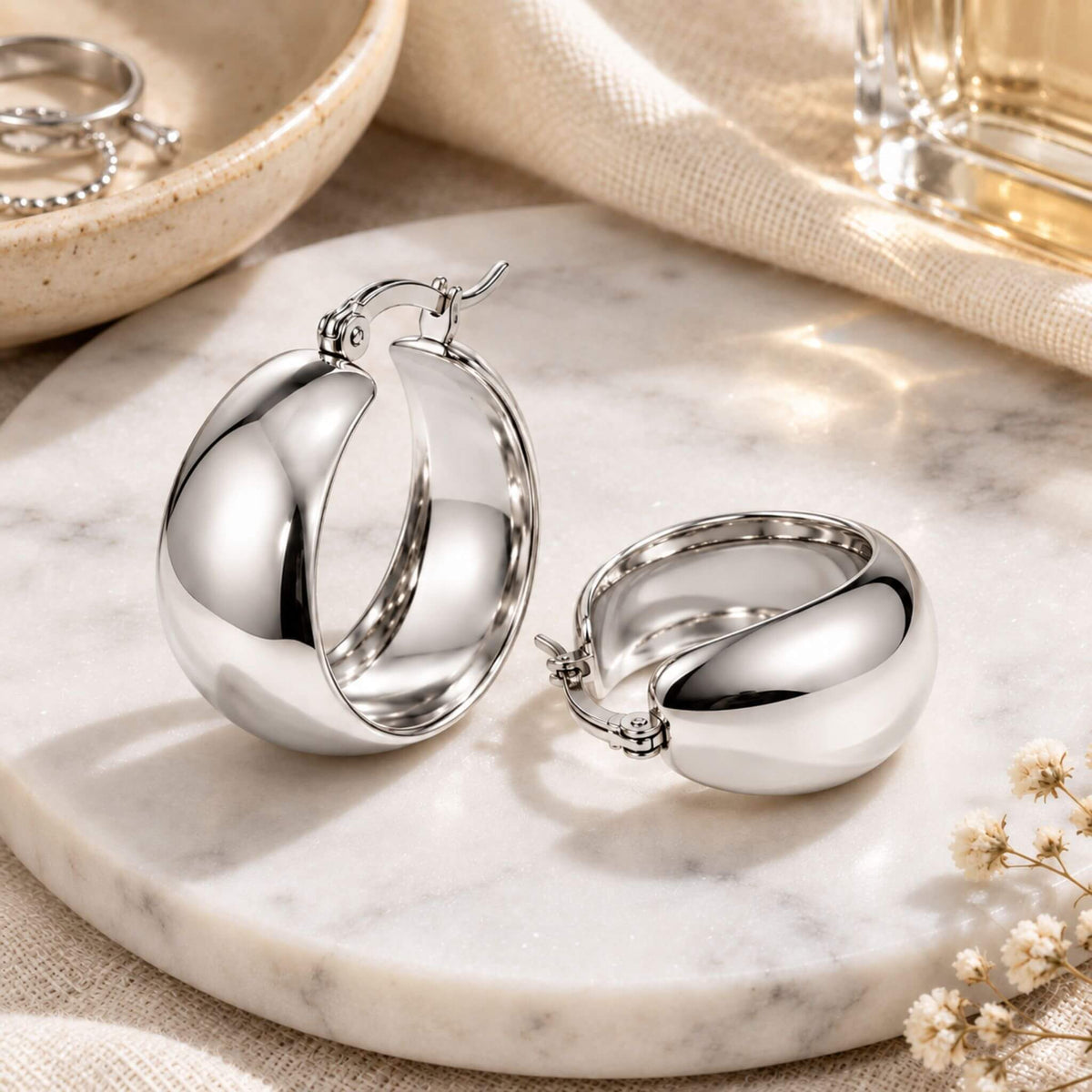 Silver chunky hoop earrings styled on a marble surface