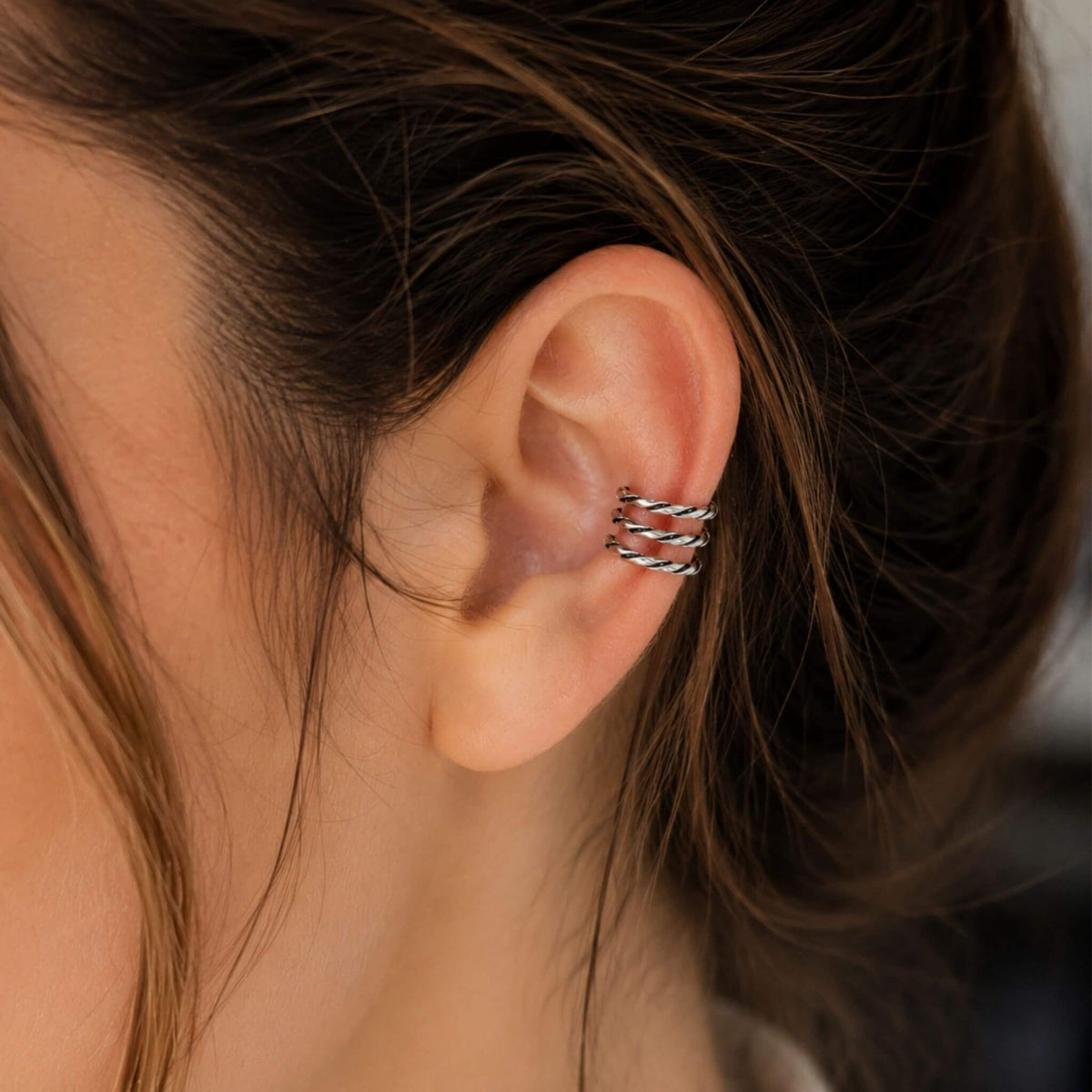 Close-up of a silver ear cuff no piercing featuring a twisted sterling silver cartilage ear cuff.