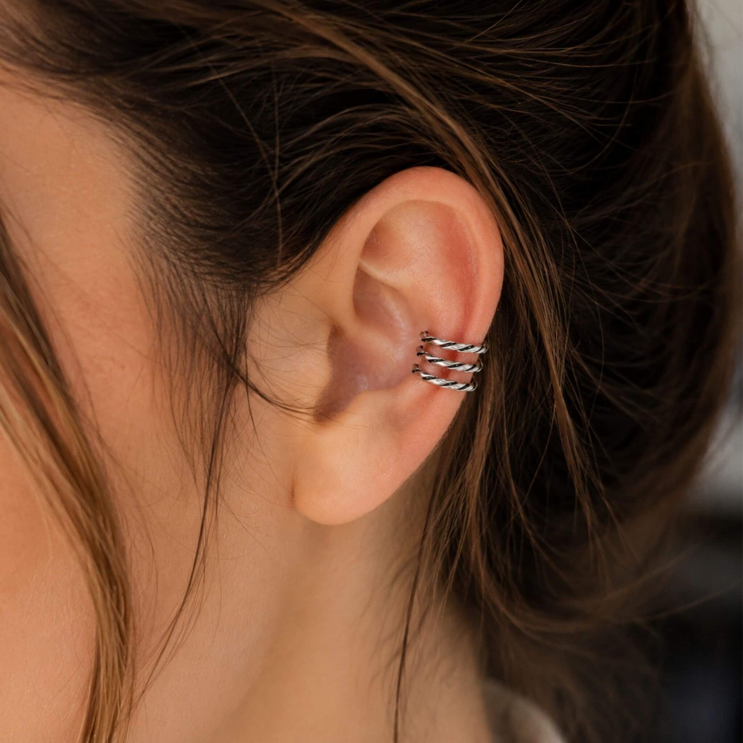 Close-up of a silver ear cuff no piercing featuring a twisted sterling silver cartilage ear cuff.