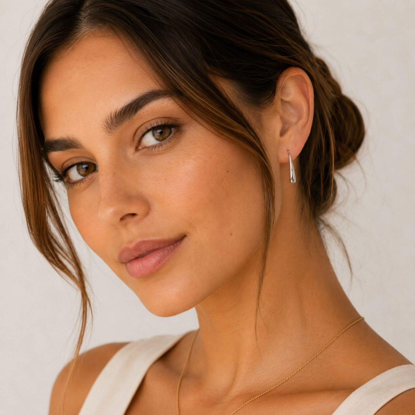 Model wearing polished silver stainless steel teardrop hook earrings for women. Lightweight hypoallergenic teardrop hook earrings for sensitive ears.