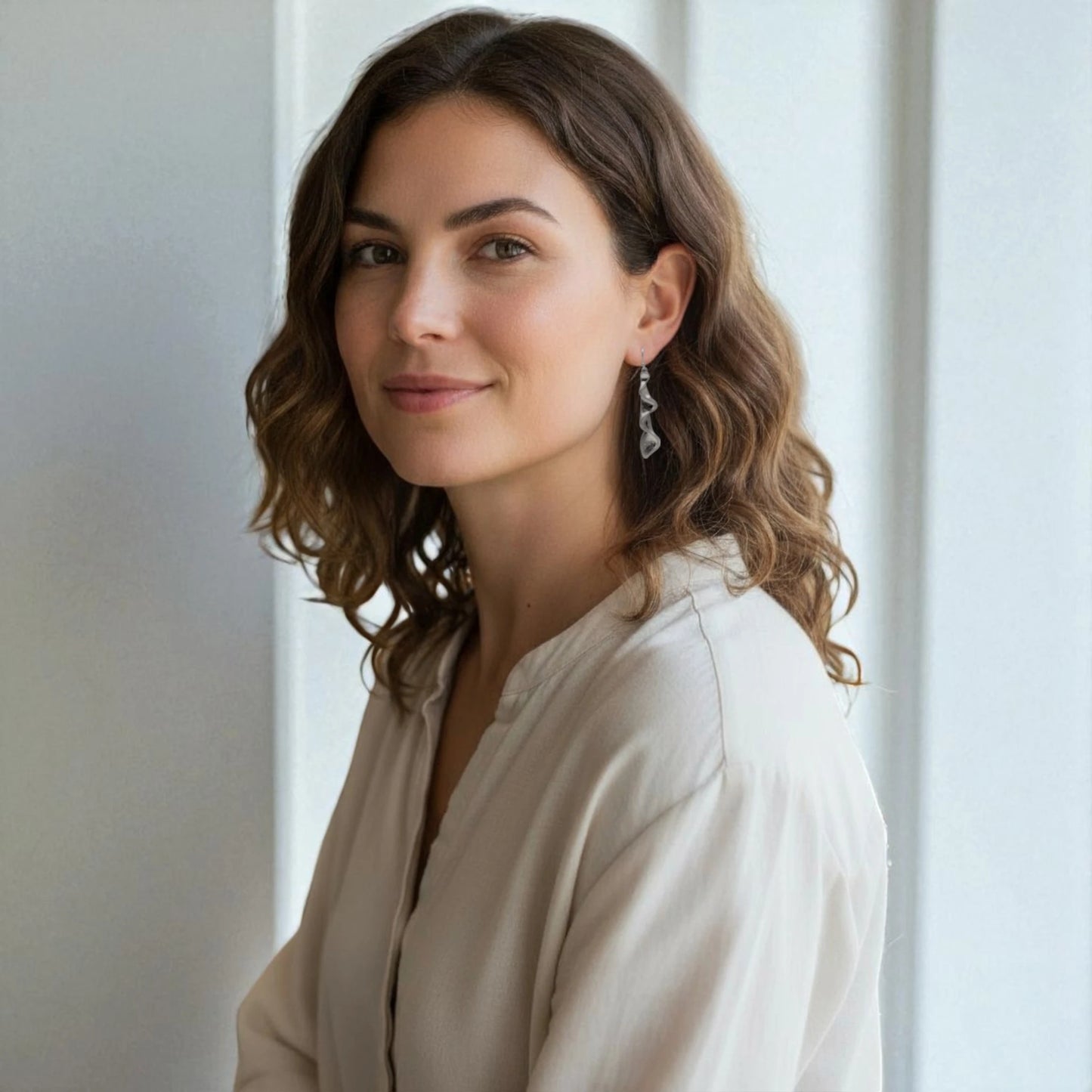 Brunette woman wearing silver wave drop earrings – elegant coastal-inspired statement jewelry by SeaSpray Jewelry