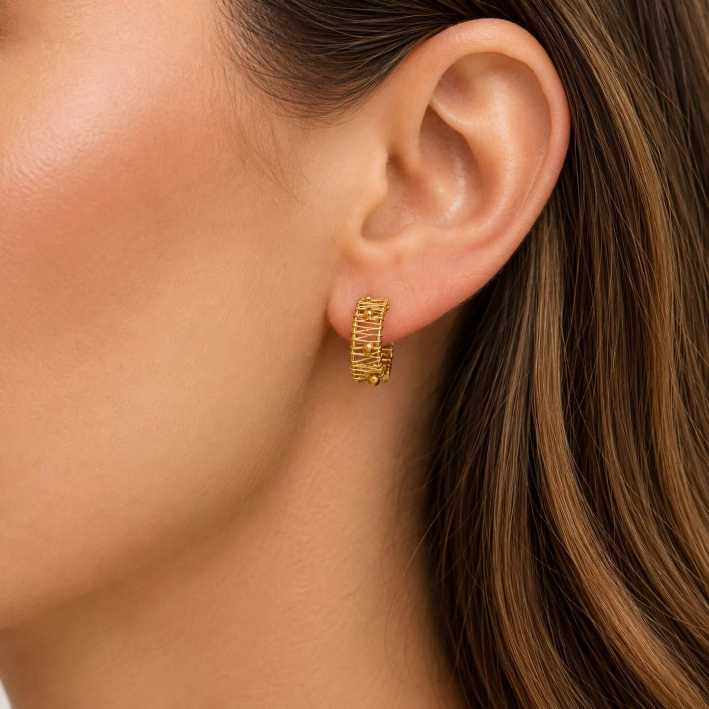 Small gold hoop earring on ear showing the wire wrapped half hoop design and polished gold beads