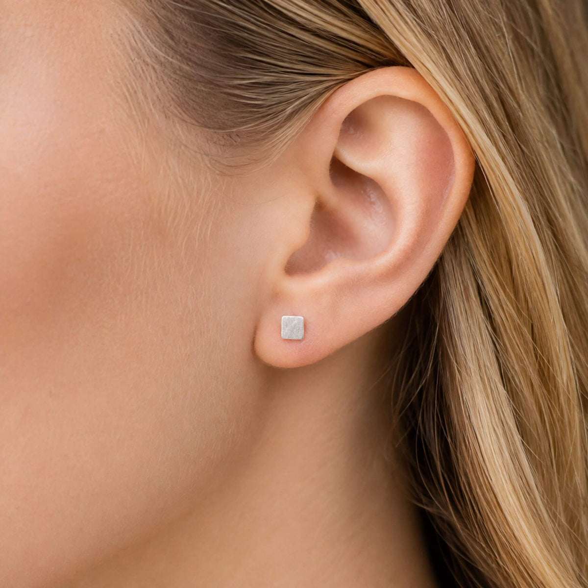 Small sterling silver square stud earrings worn on ear