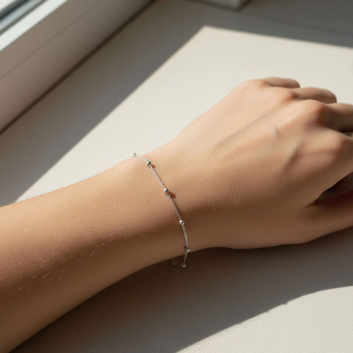 Sterling silver ball chain bracelet shown on wrist in natural sunlight