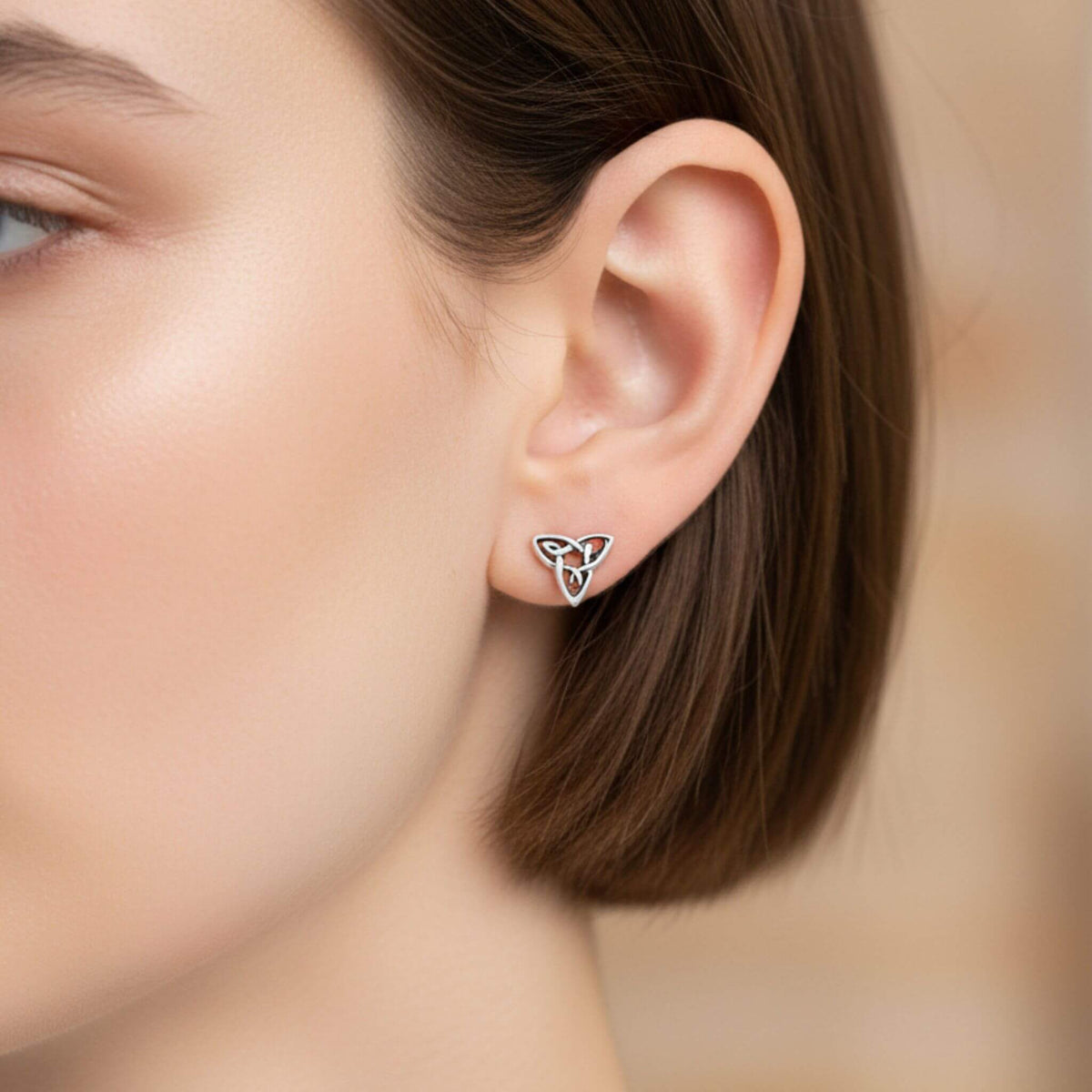 Sterling silver Celtic trinity knot stud earrings worn on ear, traditional Irish design