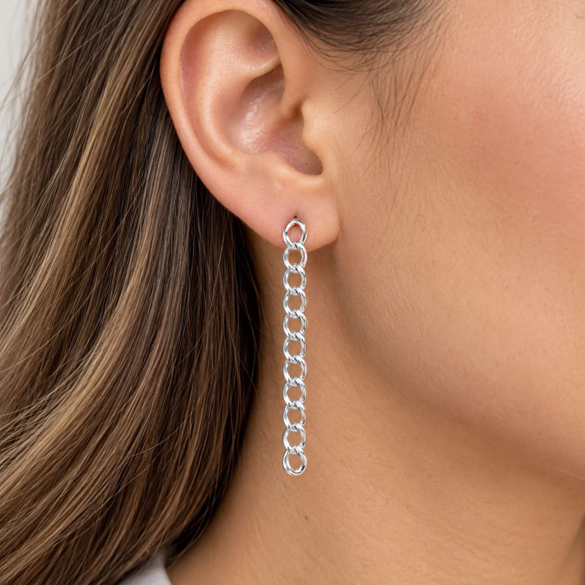 Sterling silver dangle earrings with long curb chain links worn on ear