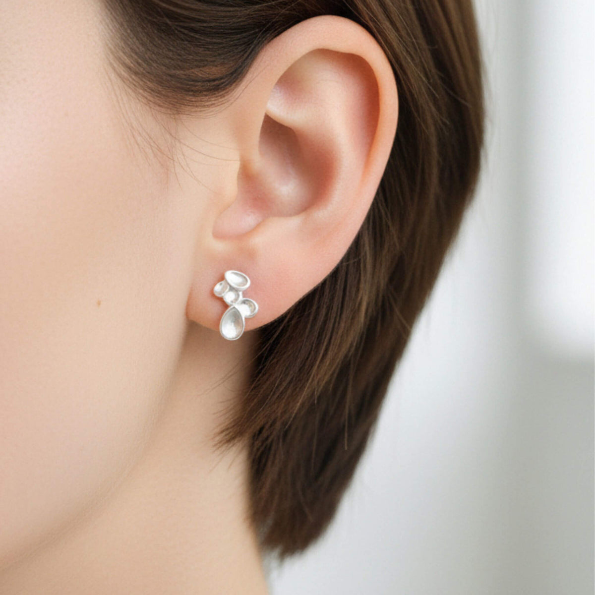 Sterling silver droplet stud earrings worn on ear