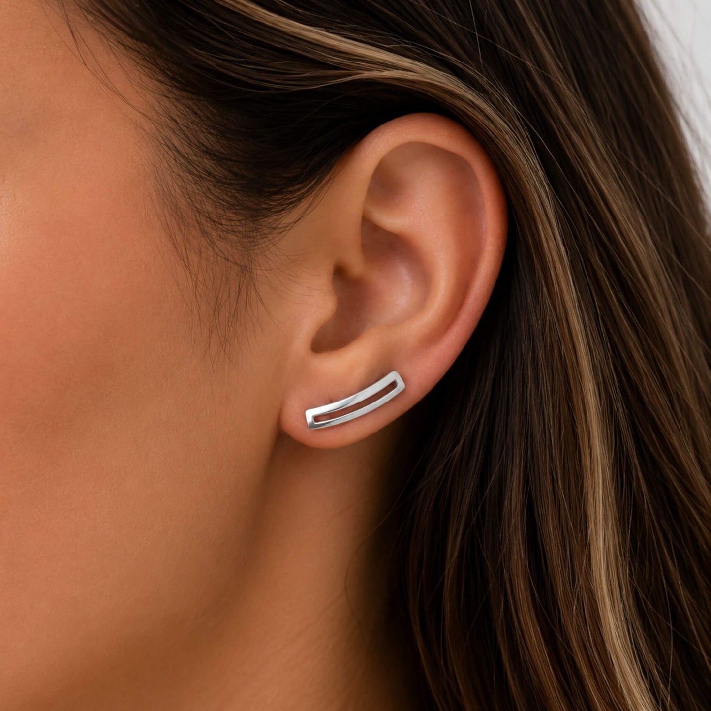 Close-up of sterling silver geometric ear climber earrings worn on the ear.