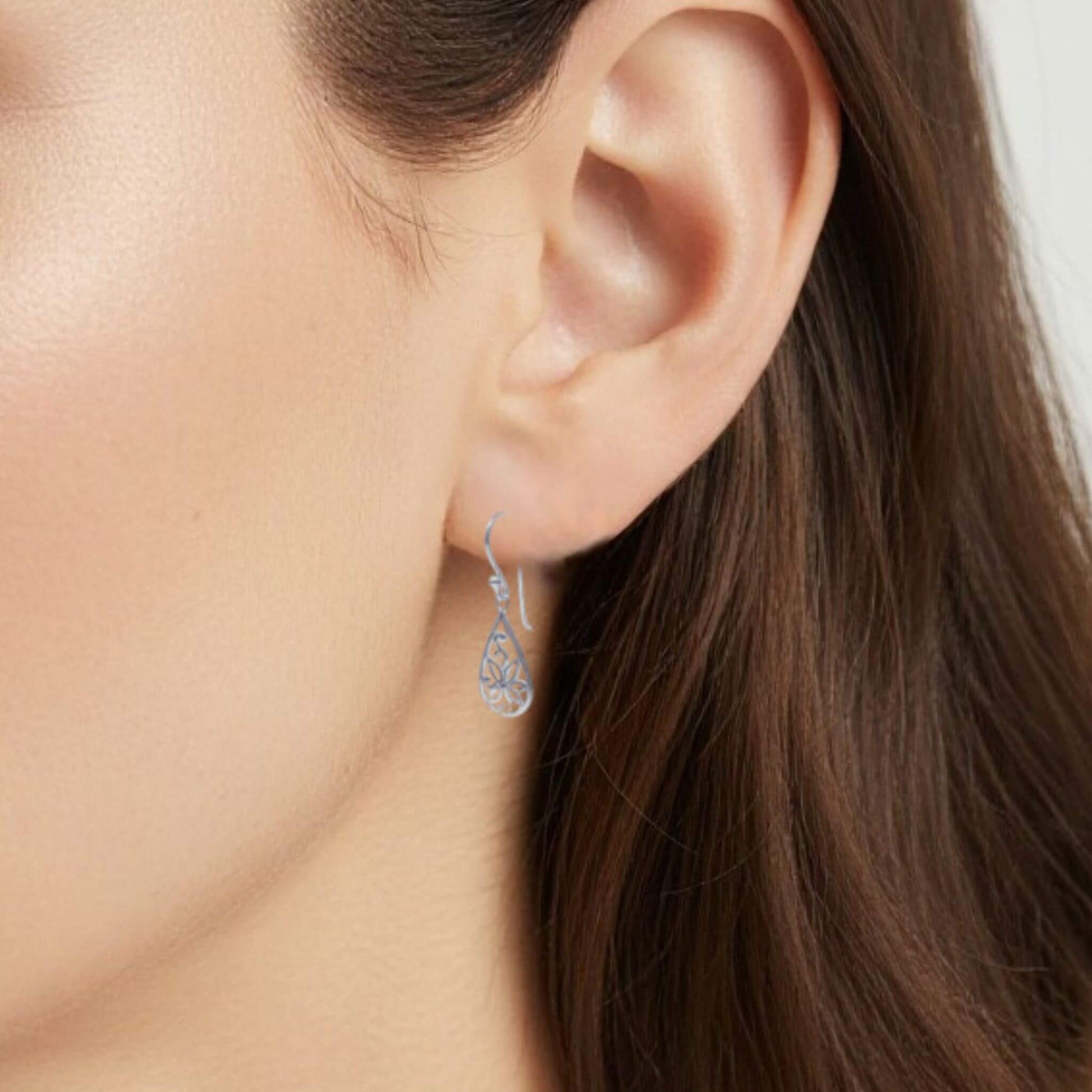Sterling silver floral drop earrings worn on model close up