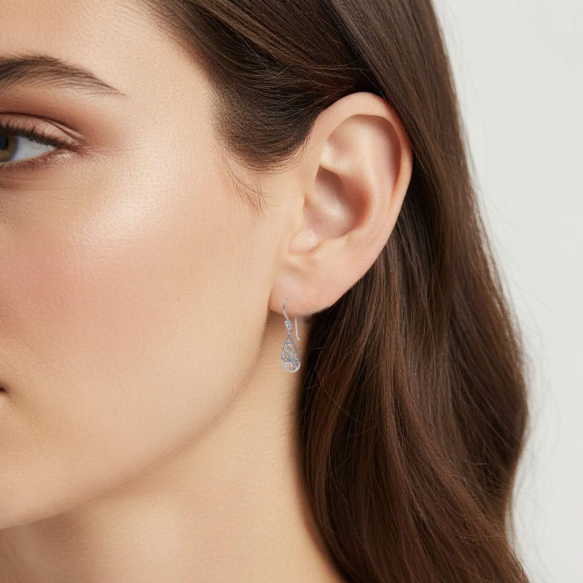 Sterling silver floral drop earrings worn on model close up
