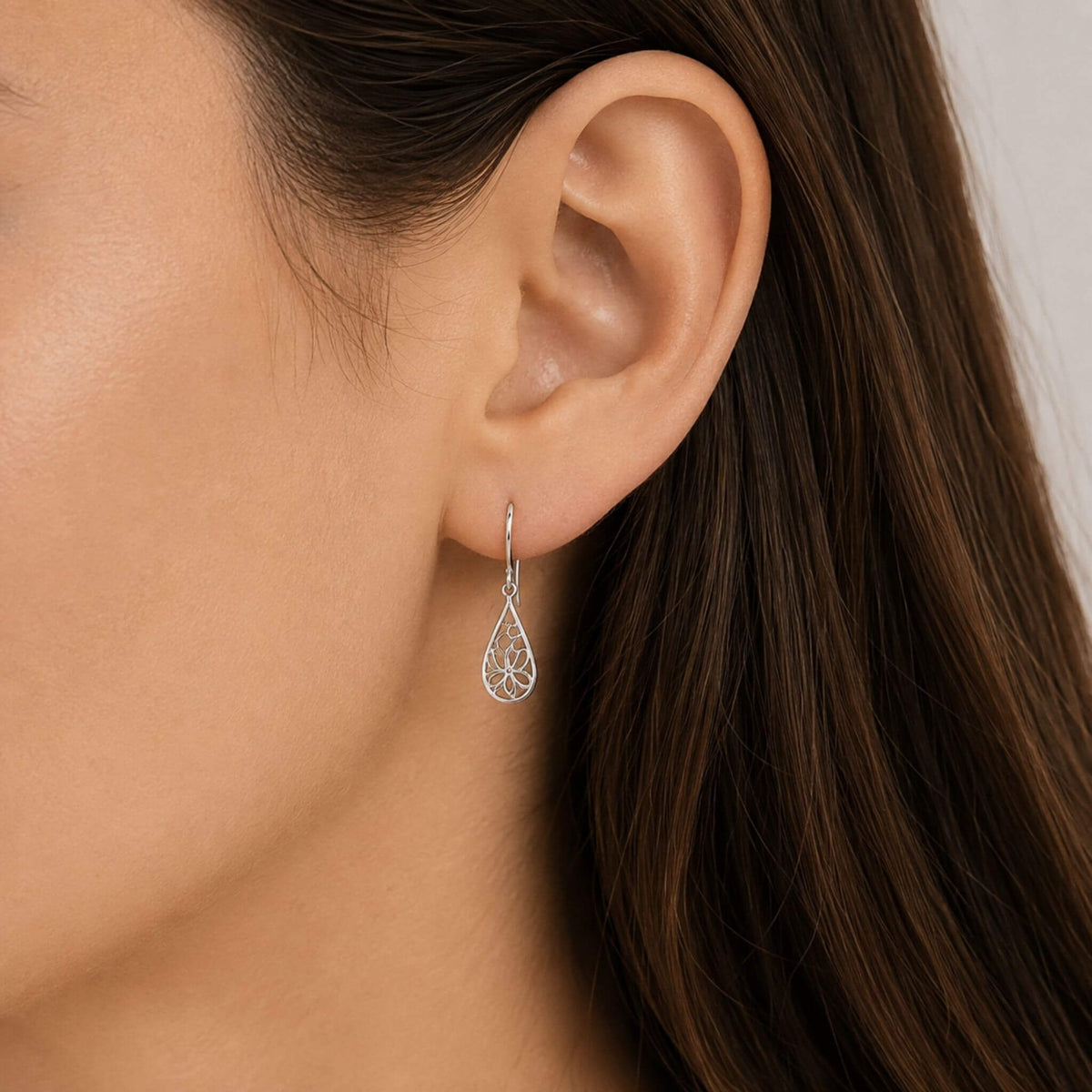 Sterling silver flower drop earring shown on ear for size and scale