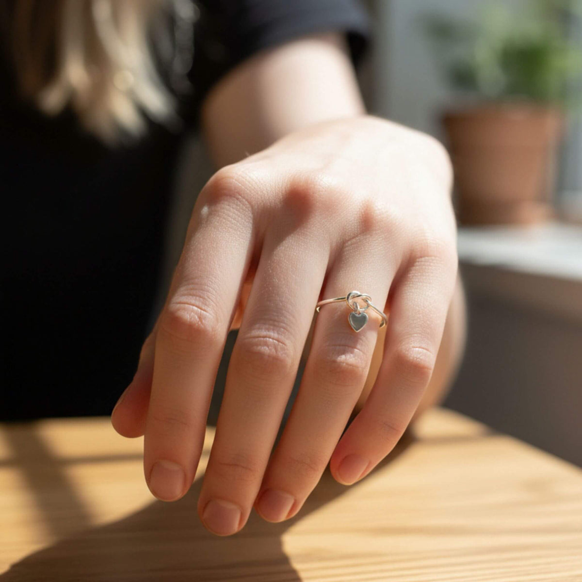 Sterling silver heart love knot ring on woman's finger, minimalist dainty jewelry