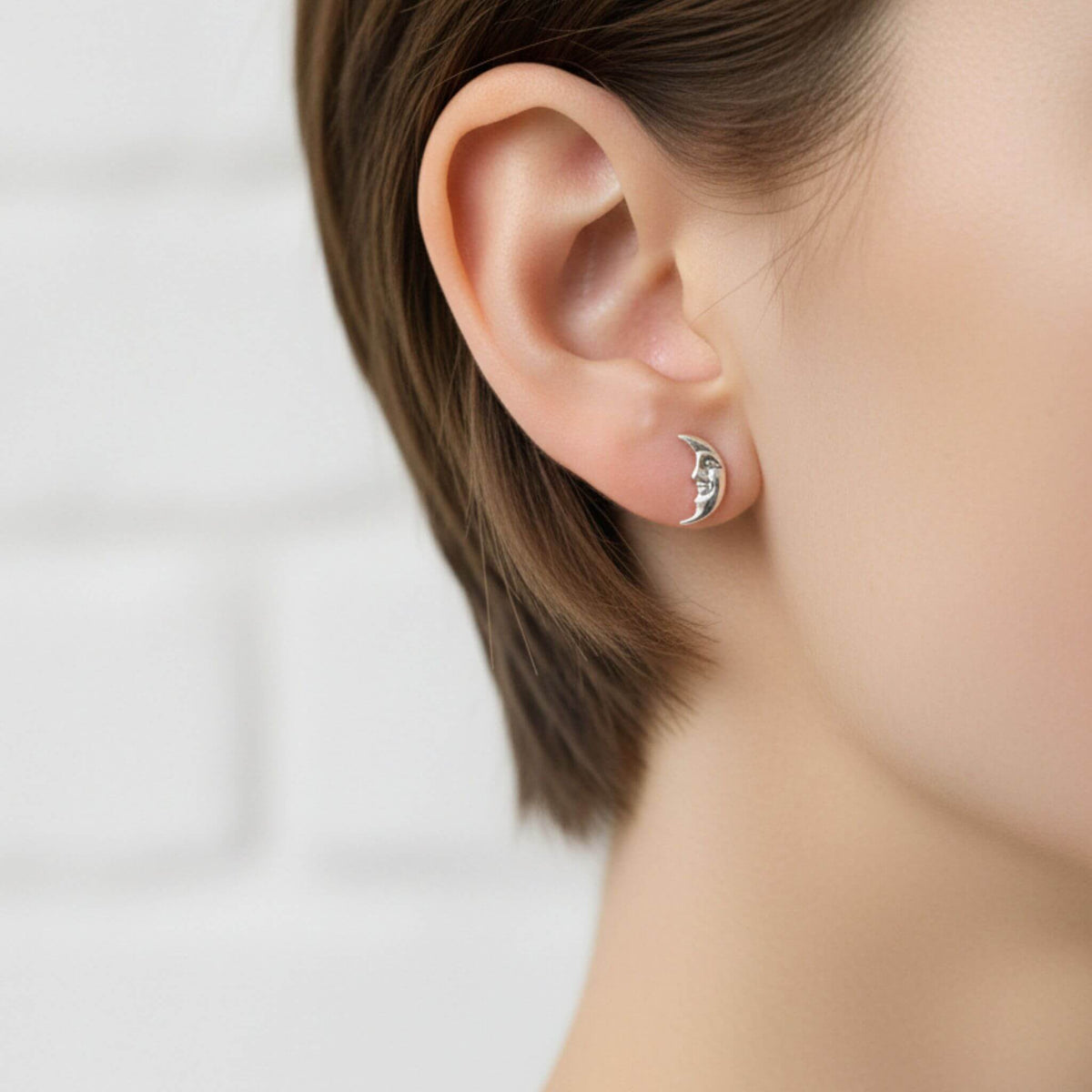 Sterling silver crescent moon stud earring worn on ear
