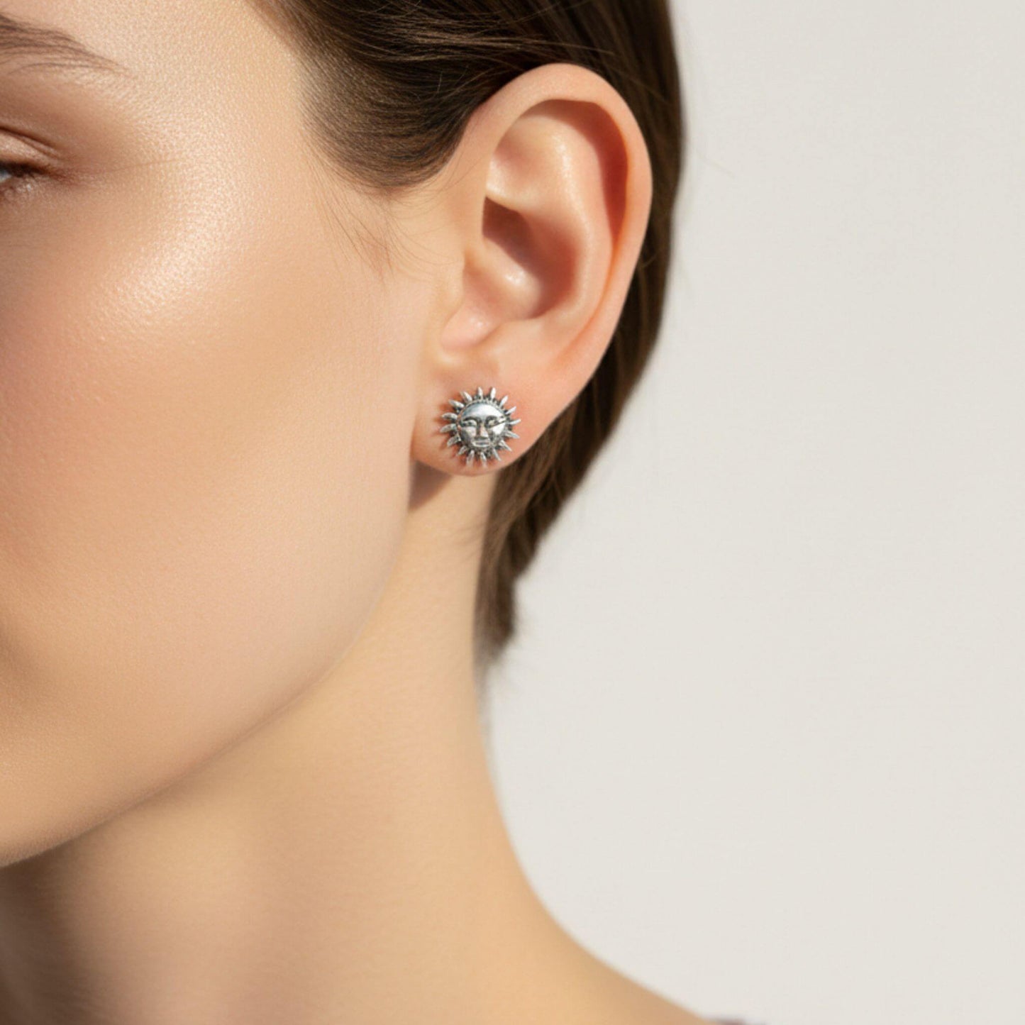 Sterling silver sun face stud earring worn on ear